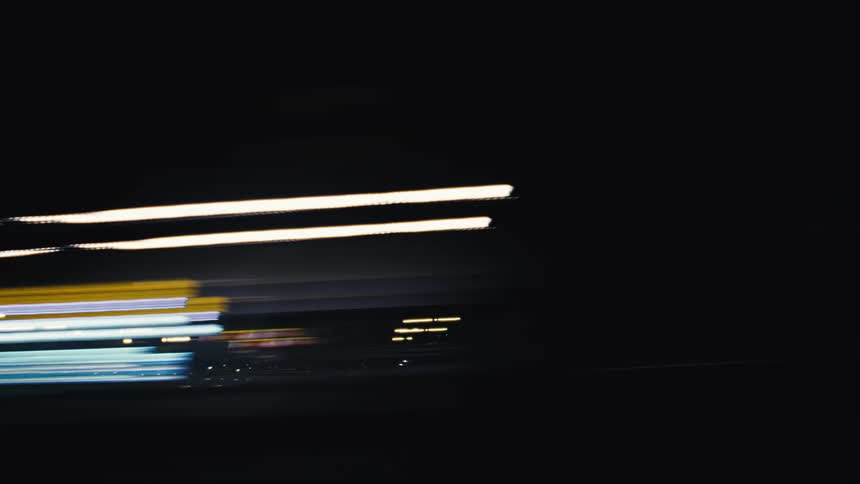 Abstract and colorful light trails streak across the screen in a dynamic time-lapse of a night drive through the city