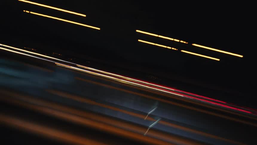 Dynamic time-lapse footage shows abstract patterns of blurred city and traffic lights at night