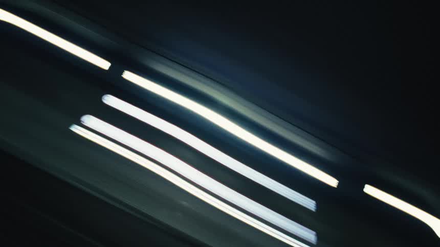 Streaks of colorful lights blur past in a dynamic, abstract time-lapse of a nighttime drive