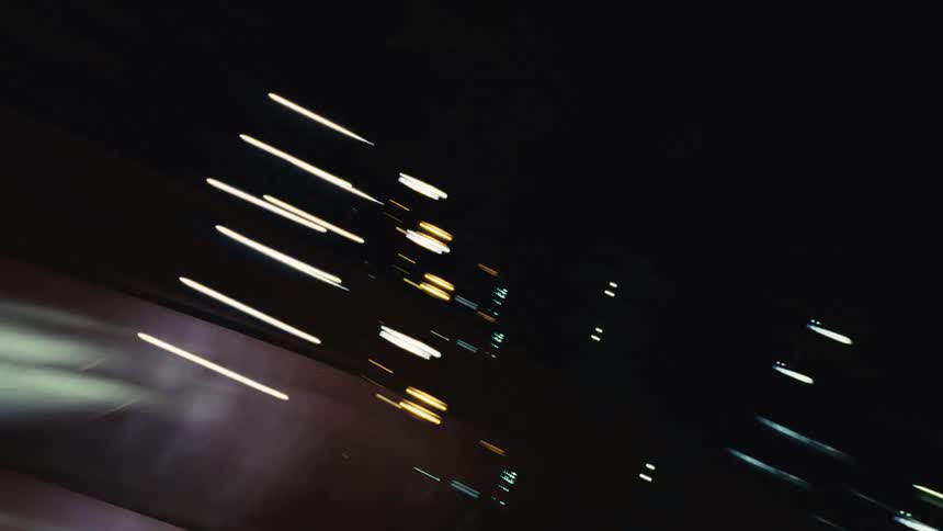 Energetic and abstract streaks of colorful city lights blaze across the screen at night