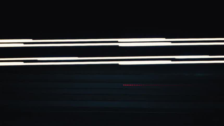 Abstract motion blur of colorful city lights and traffic streaking by at night in a dark tunnel