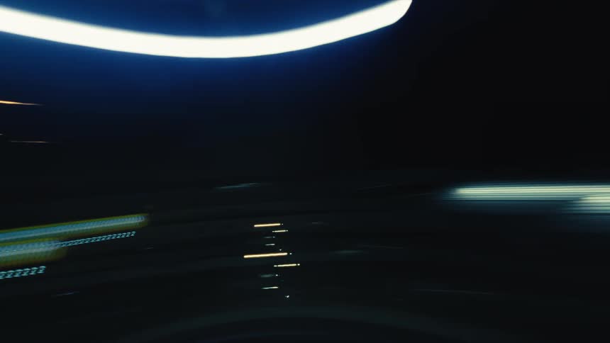 Colorful streaks of light from cars and streetlights create an abstract blur during a high-speed nighttime drive through the city