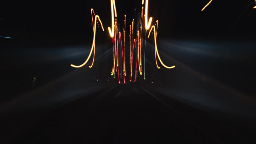 A hypnotic point-of-view time-lapse captures the abstract beauty of colorful light trails while driving through a city at night