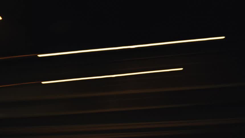 Dynamic abstract streaks of colorful city lights blur across the screen in a fast-paced night drive
