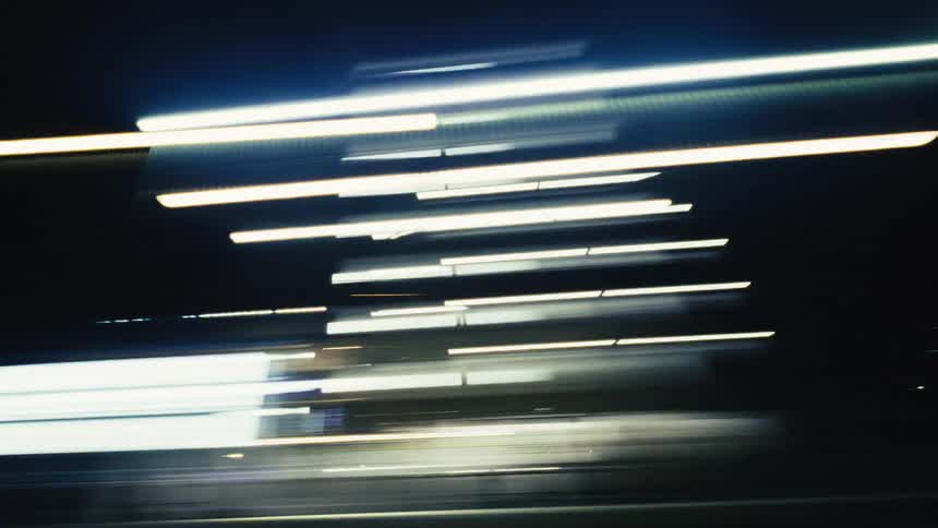 Abstract streaks of colorful city lights blur past the camera at night from a moving vehicle