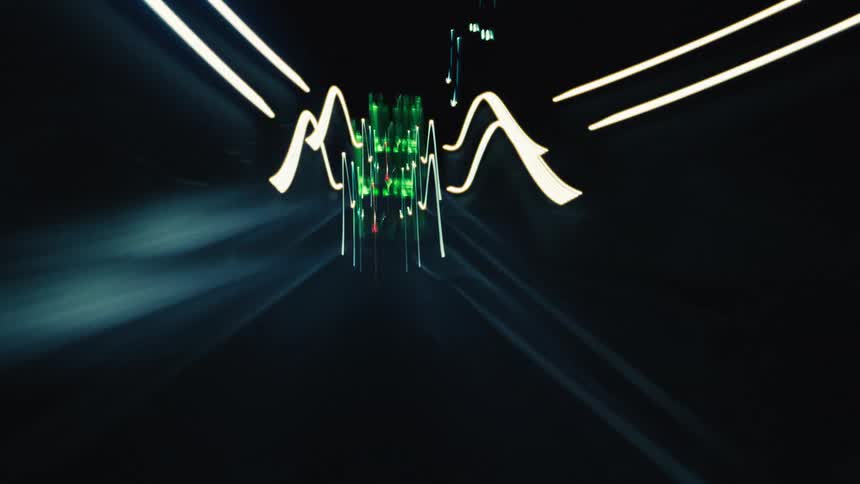 A surreal point-of-view time-lapse of driving at high speed through city streets and tunnels at night, creating abstract light trails