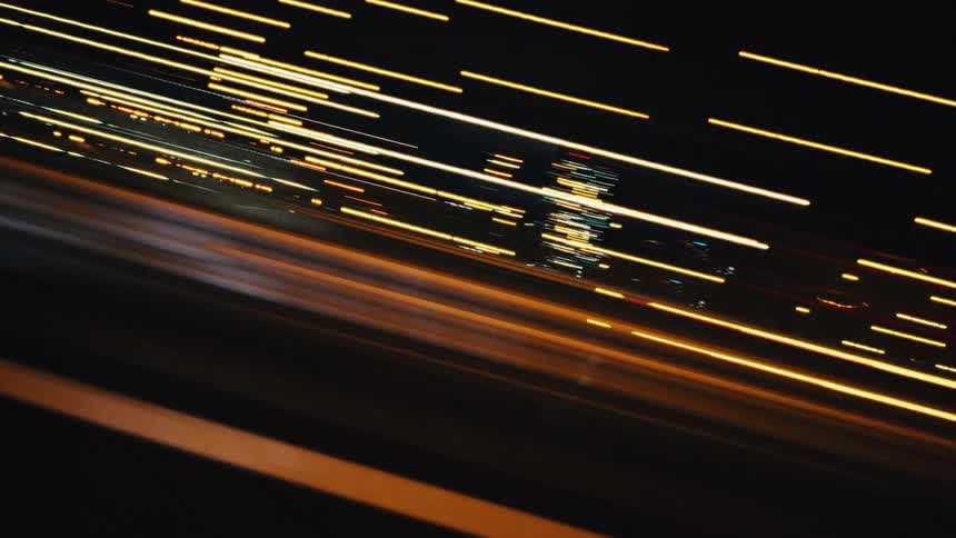 Dynamic streaks of colorful lights from city traffic at night create an abstract motion blur effect