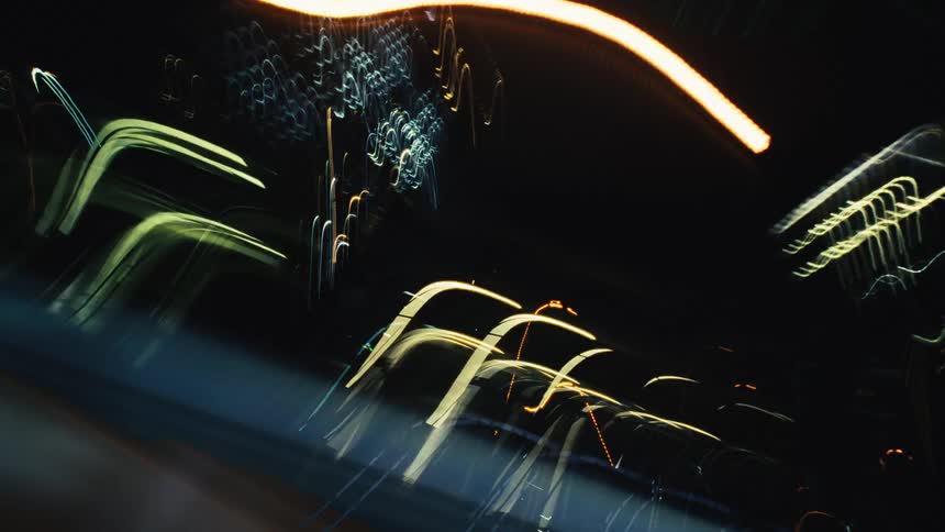 Dynamic motion blur of colorful city lights at night creates an abstract, energetic, and futuristic visual