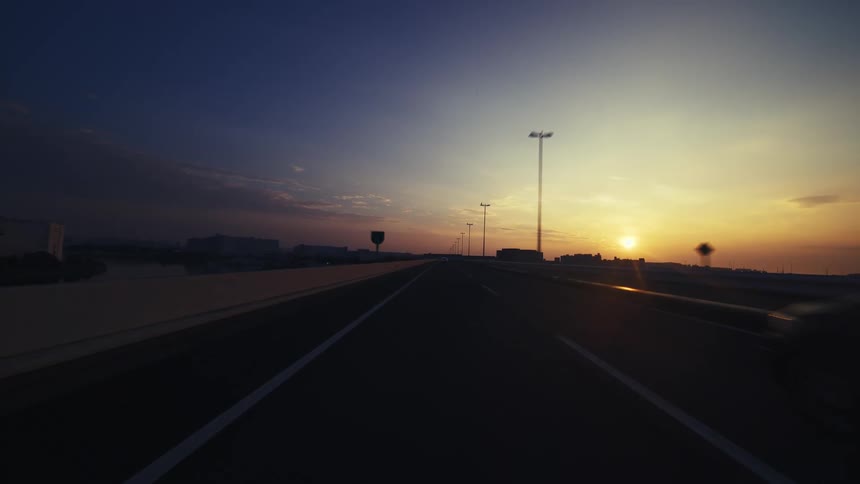 A serene point-of-view drive along an empty highway into the golden glow of a beautiful sunrise