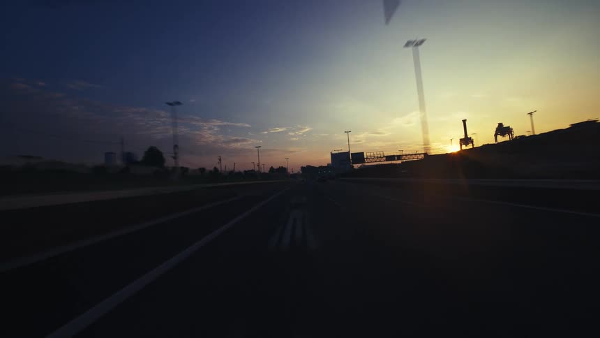 A dreamy time-lapse from a car driving on an empty highway towards the golden sunrise