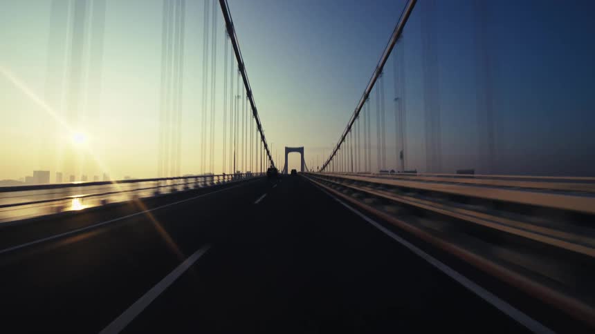 Dizzying first-person time-lapse drive across Tokyo's iconic Rainbow Bridge as the sun rises over the city
