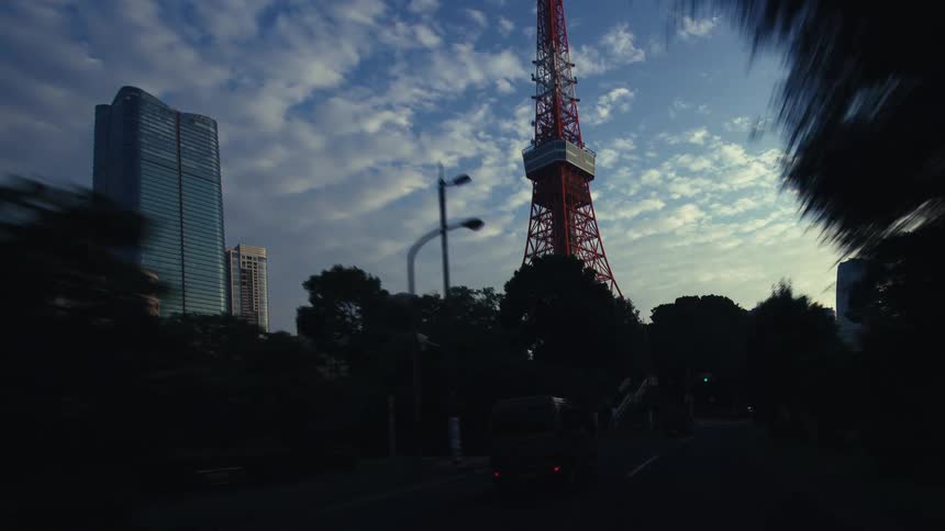 A slow, cinematic point-of-view drive towards the iconic Tokyo Tower against a beautiful morning sky
