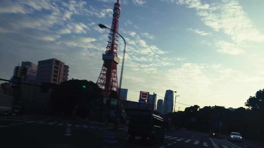 A slow drive through the quiet streets of Tokyo, approaching the iconic Tokyo Tower against a beautiful morning sky
