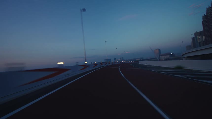 A driver's point-of-view journey along a modern, empty highway interchange with red pavement at twilight