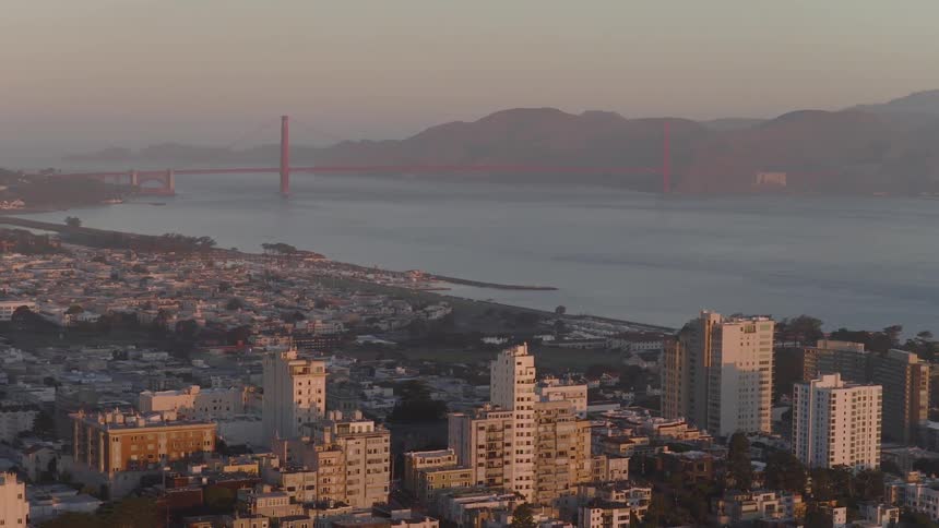 A stunning aerial view of San Francisco and the Golden Gate Bridge bathed in the warm light of a hazy sunrise