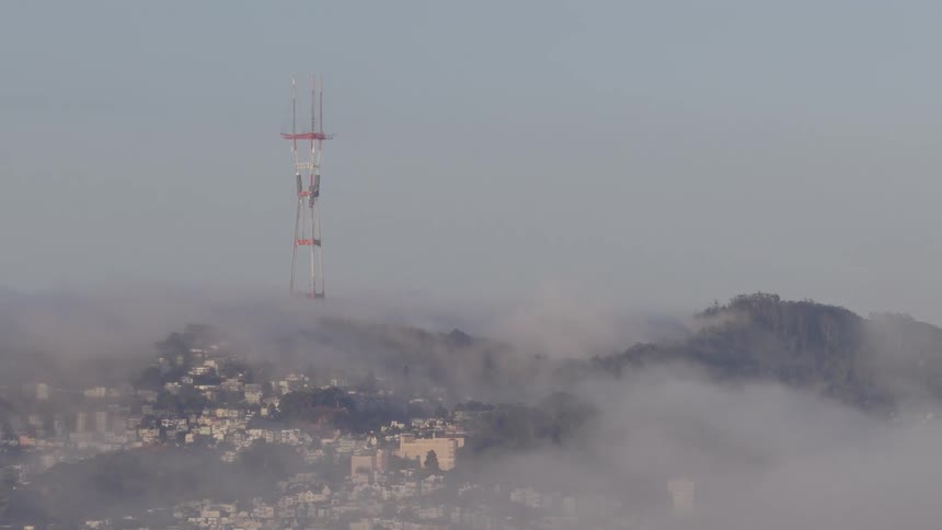 A slow pan across a foggy San Francisco skyline reveals an American flag waving on a skyscraper, with the iconic Sutro Tower visible in the distance