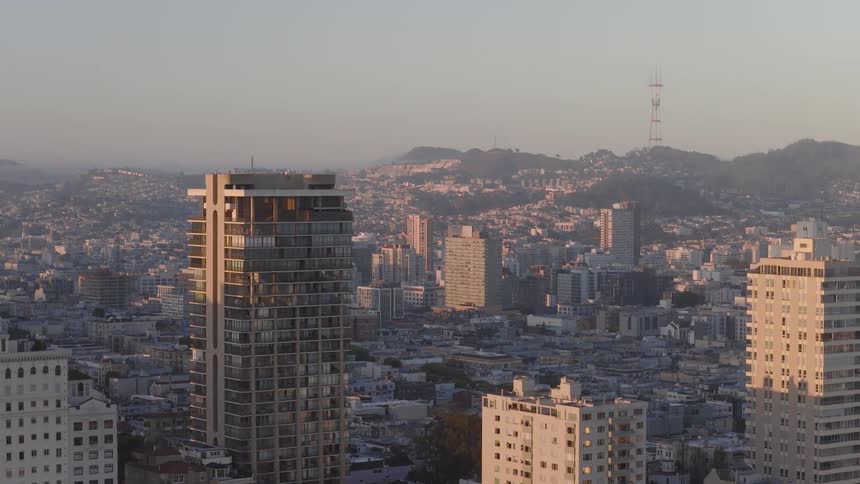 A slow aerial view of the San Francisco skyline and the Sutro Tower in the distance during a beautiful sunrise