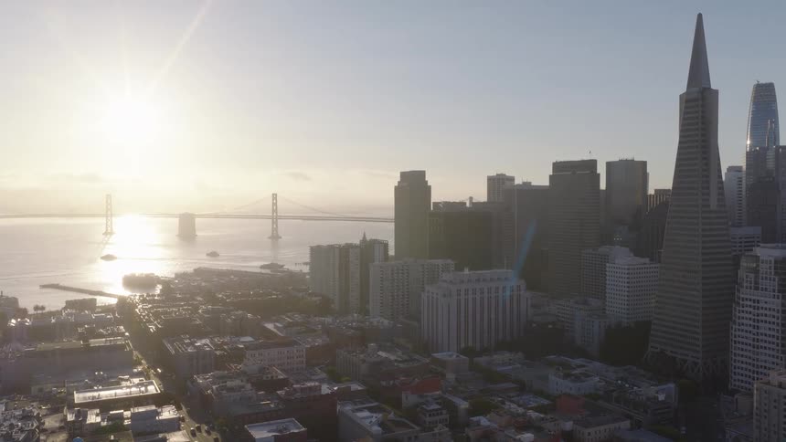 A majestic aerial shot captures the San Francisco skyline, including the Transamerica Pyramid, bathed in the warm glow of sunrise over the bay