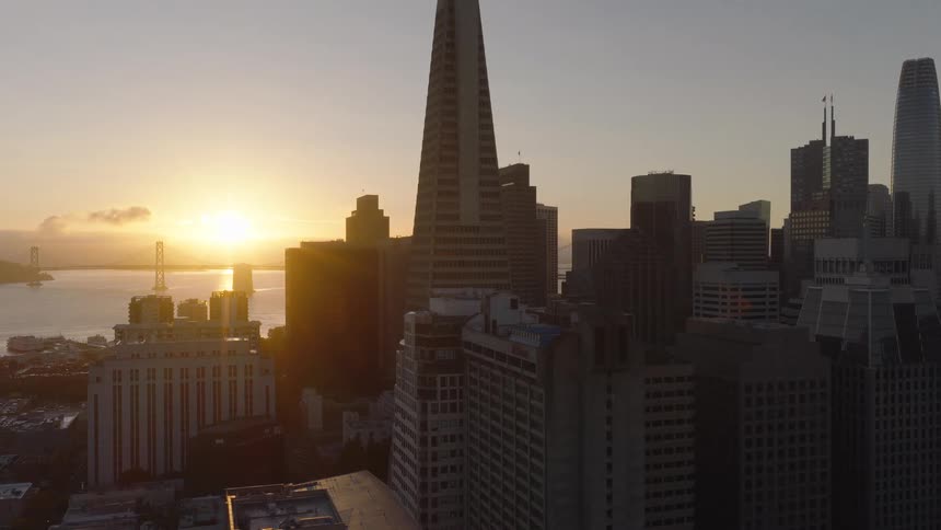 A majestic aerial view of the San Francisco skyline, including the Transamerica Pyramid and Bay Bridge, glows during a beautiful sunrise