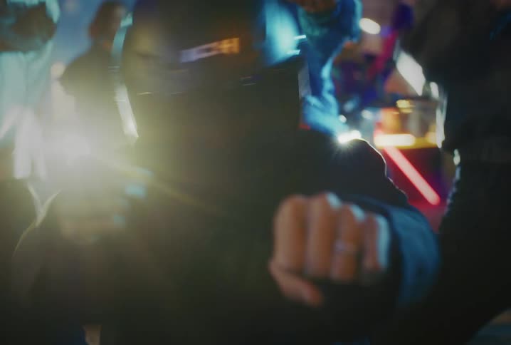 Close up of energetic dancers wearing motorcycle helmets performing a synchronized routine at a street party at night