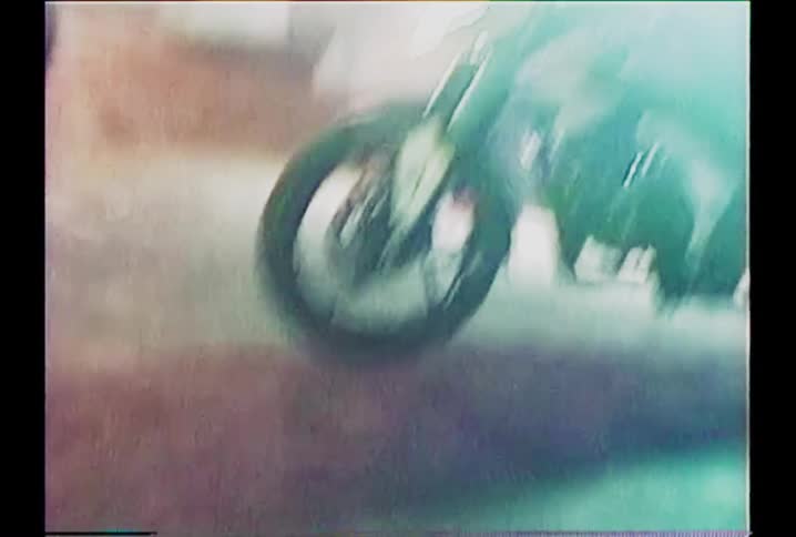 An abstract and blurry handheld shot captures motorcycles on a cobblestone street at night, with a distinct vintage film look