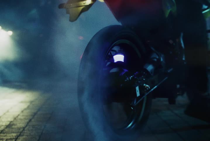 Close-up of a motorcycle tire spinning and smoking during a burnout on a city street at night