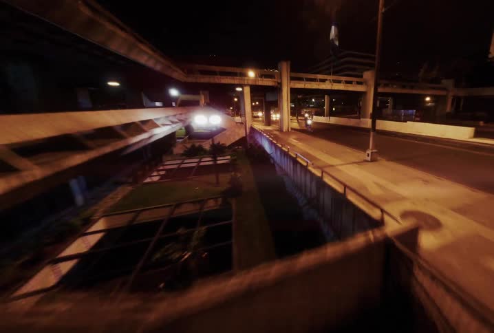 A first-person perspective shot moving quickly through a dark urban underpass at night towards city traffic