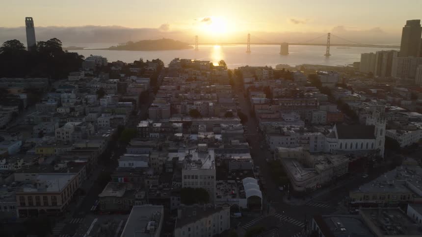 A stunning aerial view pans from Coit Tower across the San Francisco cityscape to reveal the downtown skyline as the sun rises over the Bay Bridge