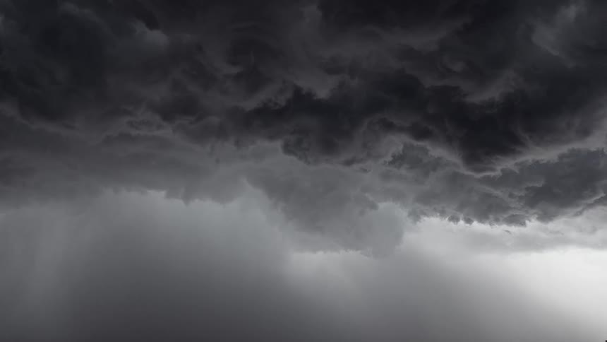 An ominous sky is filled with dark, turbulent storm clouds and heavy falling rain