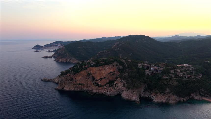 A beautiful aerial view of the rocky Costa Brava coastline in Spain during a serene sunset