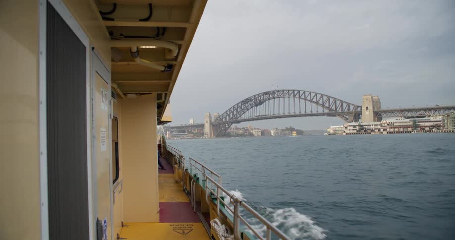 A view of the Sydney Harbour Bridge from the deck of a moving ferry on an overcast day