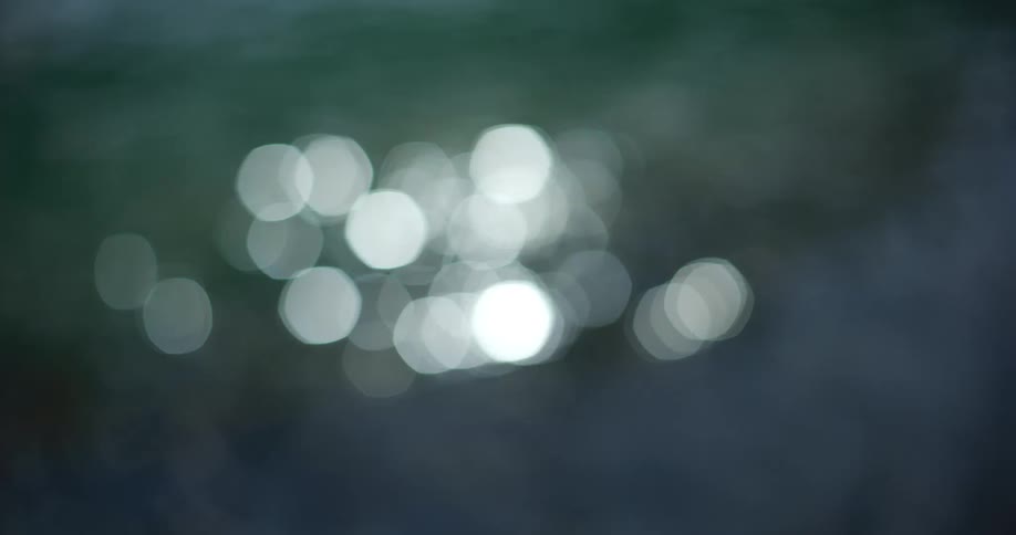 Abstract bokeh shot of sparkling light shimmering on the surface of dark water