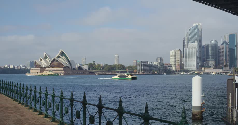 A ferry crosses the water in front of the iconic Sydney Opera House and the city skyline on a bright day