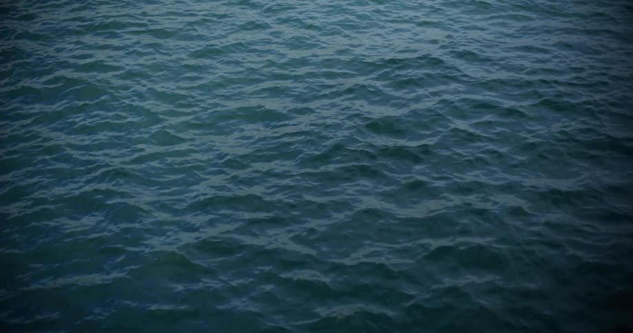 A steady shot of dark, mesmerizing ocean water rippling calmly