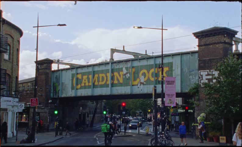 A static shot of the iconic Camden Lock railway bridge in London with traffic and pedestrians passing below
