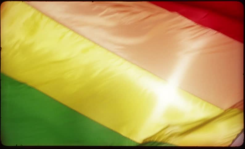 A vintage-style slow-motion close-up of a rainbow Pride flag waving gracefully as sunlight shines through its vibrant colors