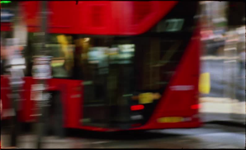 Gritty, fast-paced montage of London street life with motion-blurred shots of iconic black cabs, red buses, and a street sign in Camden