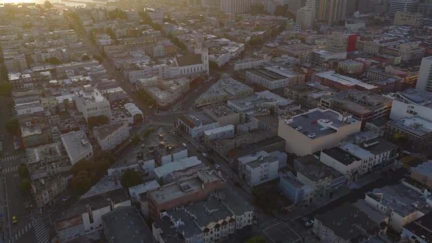 An epic aerial shot flies over a San Francisco neighborhood, tilting up to reveal the iconic city skyline and Bay Bridge bathed in the golden light of sunrise