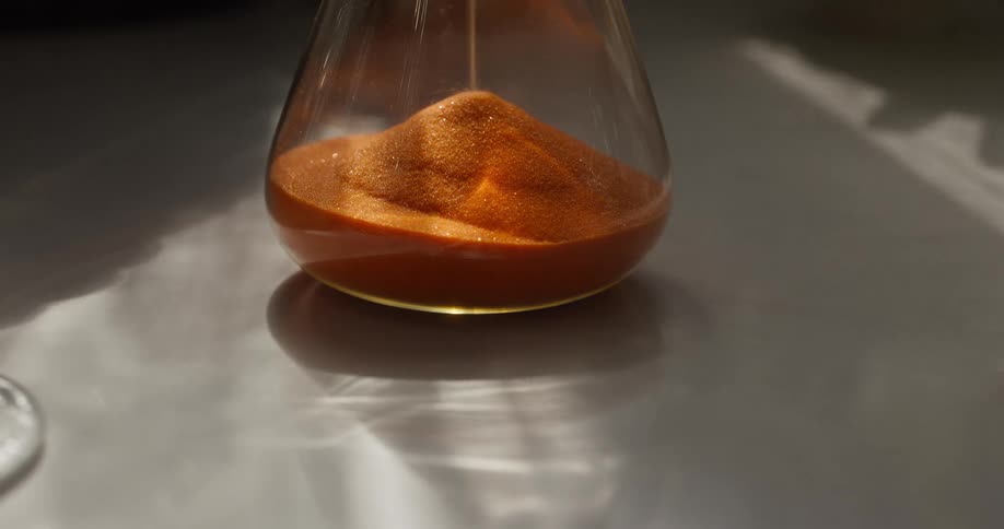 Close-up of golden sand falling through an hourglass, symbolizing the passage of time