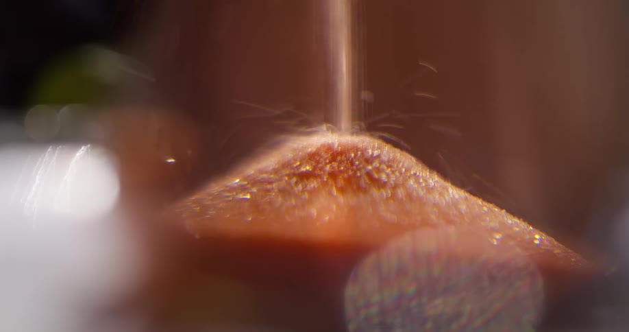 A macro close-up of golden sand flowing through an hourglass, symbolizing the passage of time