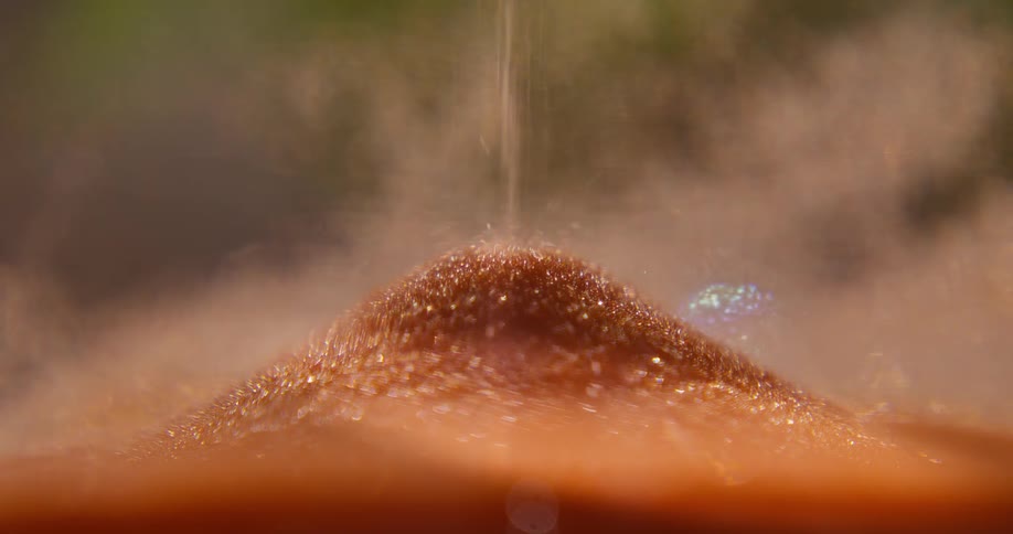 Mesmerizing macro shot of glittering golden sand falling inside an hourglass, creating a hazy and dreamlike visual