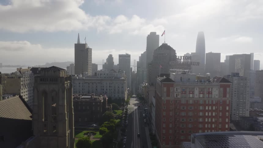 A slow pull-back aerial shot reveals the downtown San Francisco cityscape, including the Huntington Hotel and Salesforce Tower, on a hazy day