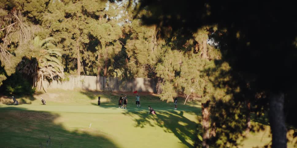 A group of friends enjoys a sunny afternoon putting on the green at a lush golf course