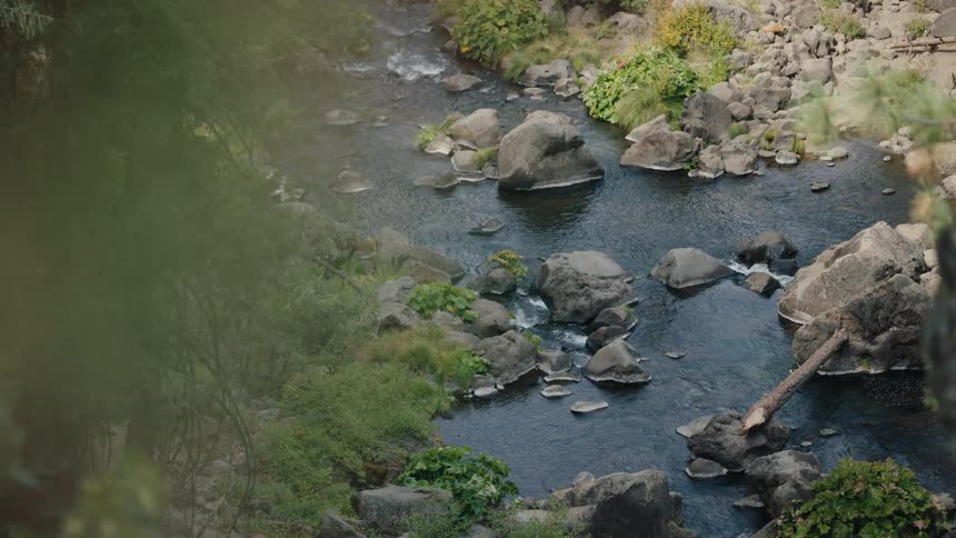 A peaceful river flows through a rocky canyon, with the camera slowly pulling back to reveal the natural scenery