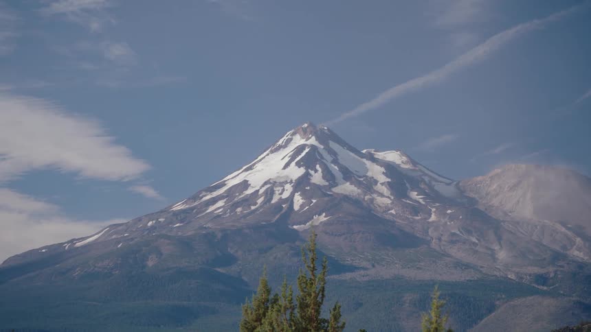 The majestic, snow-capped Mount Shasta slowly comes into focus and zooms out against a clear blue sky