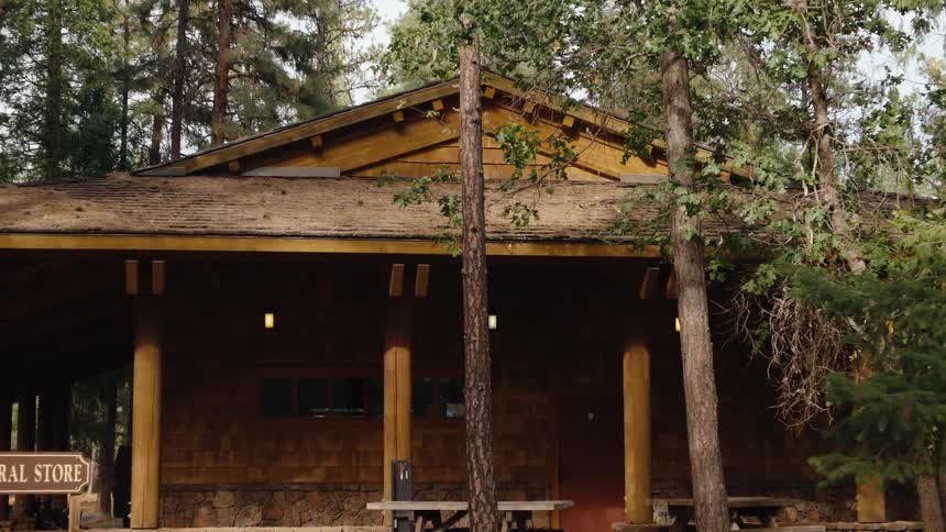 The camera quickly zooms in on a classic wooden general store located in a forest setting