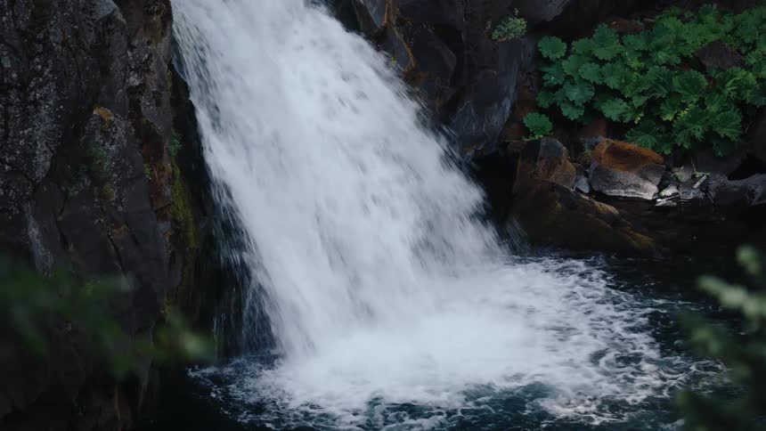 A powerful waterfall crashes into a turquoise pool, with a zoom-in to a closer shot of the rushing water