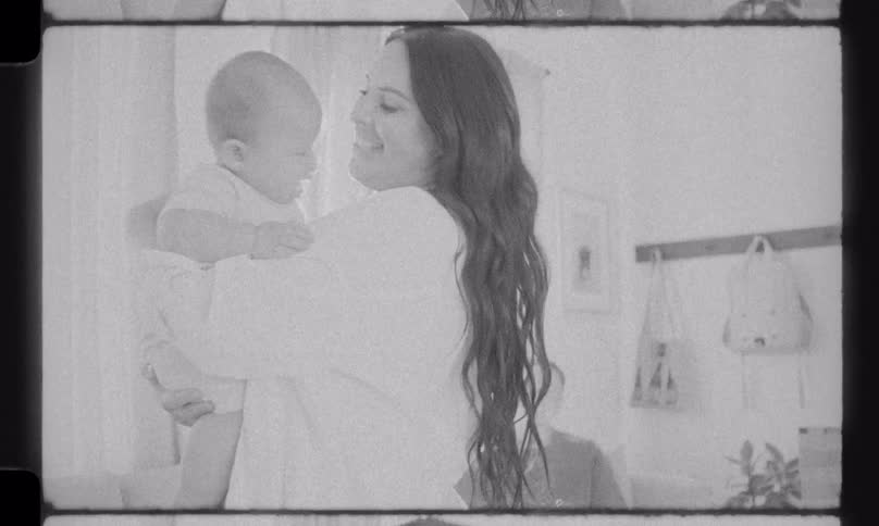 Vintage black and white footage shows a tender moment as a mother cuddles her infant in a bright nursery