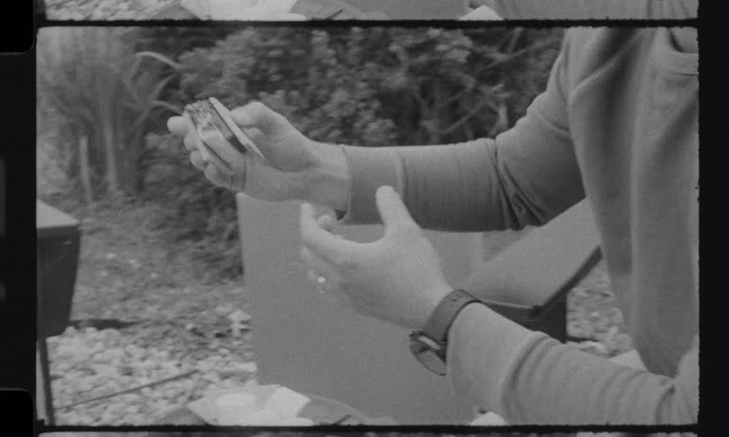 Vintage black and white footage shows a man making a s'more and happily sharing it with a young boy outdoors
