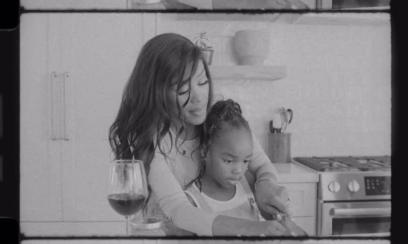 A loving mother teaches her daughter to chop vegetables on a cutting board in their bright kitchen in this nostalgic black and white clip